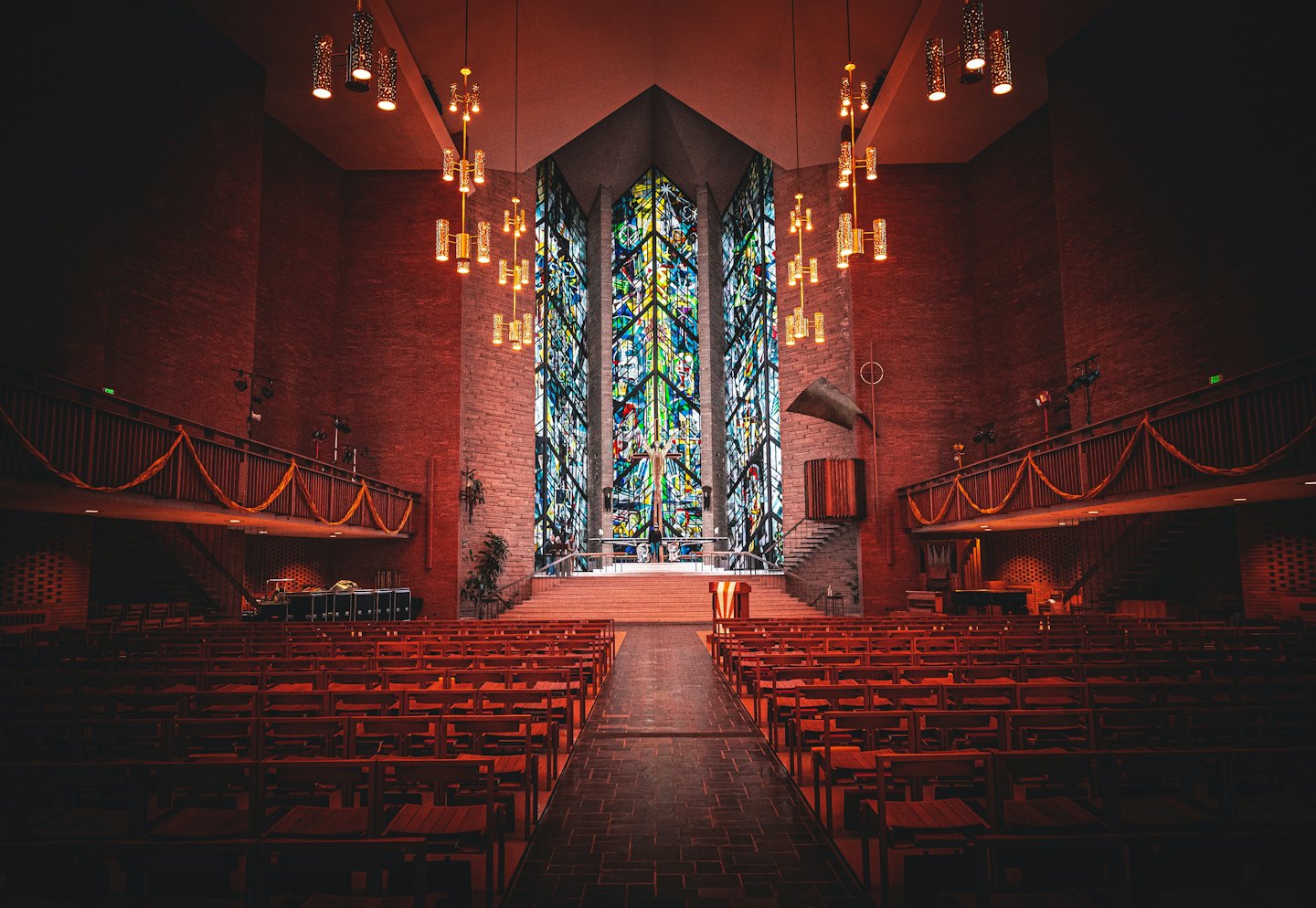 Empty wooden pews face the altar and large stained-glass window.