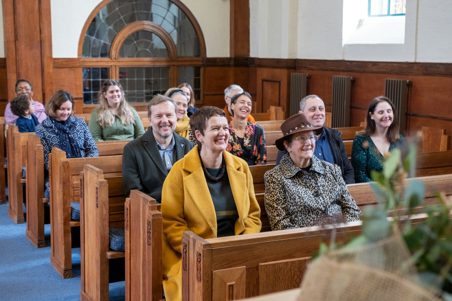 Smiling people in church pews look toward an event.