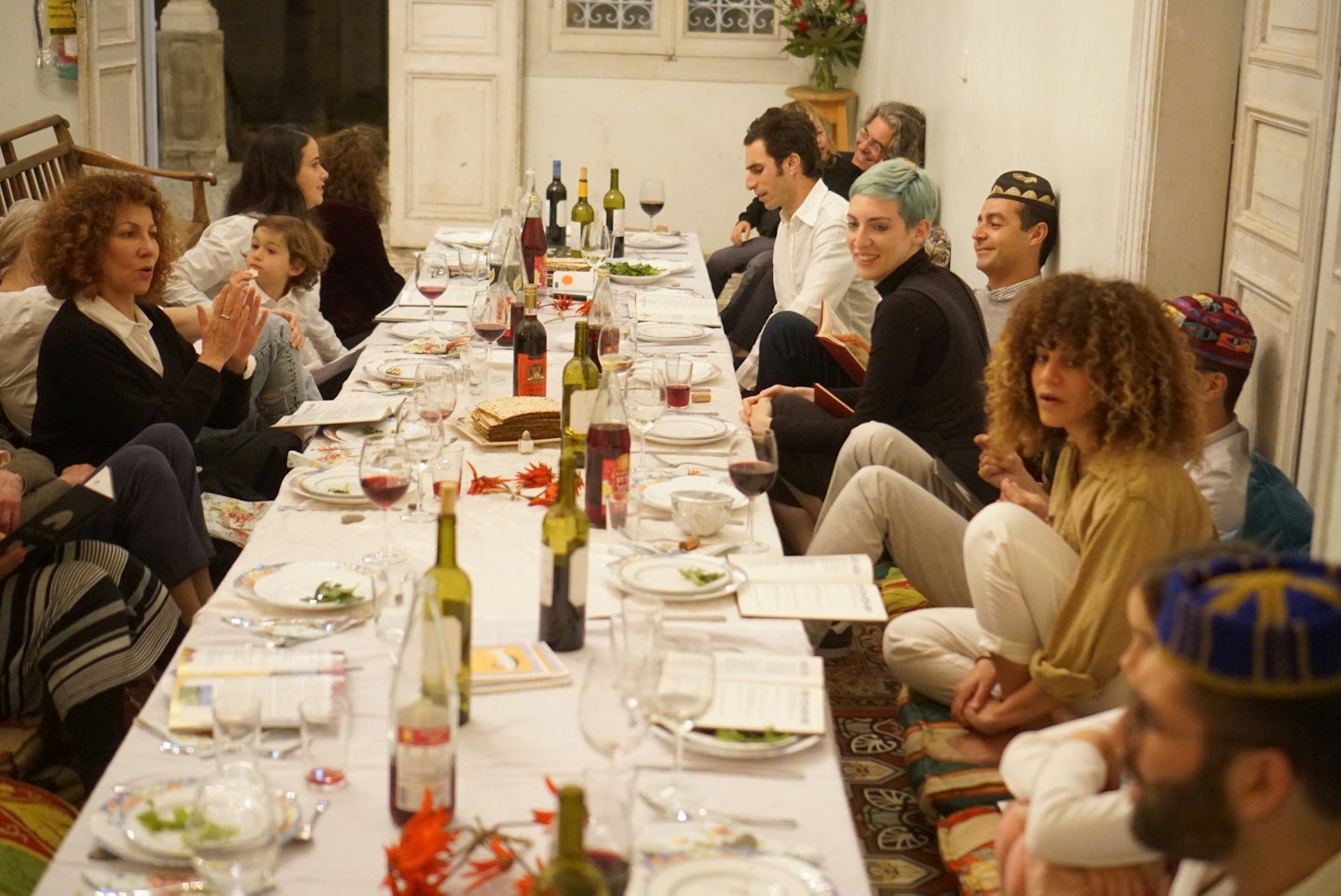 People sitting on floor cushions share a meal around a table.