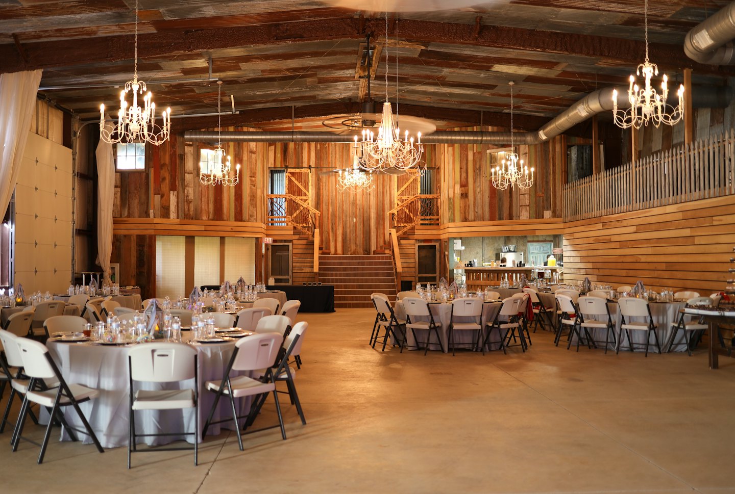 Empty event hall with round tables and white chairs.