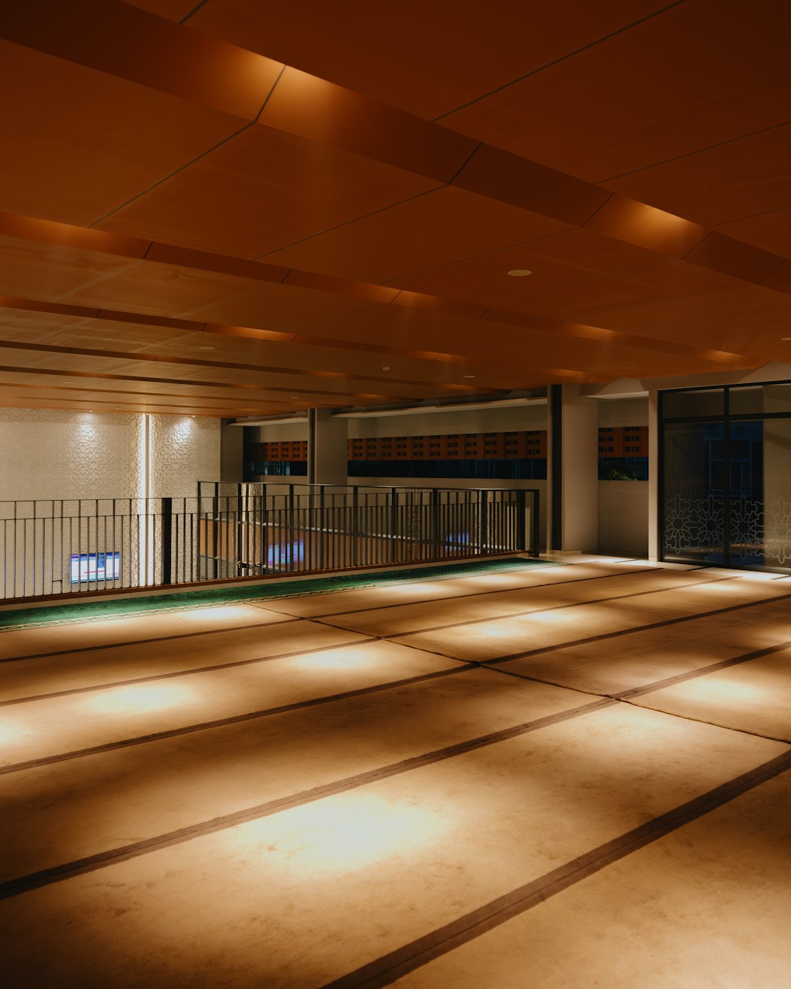 Modern prayer hall with a patterned floor and slatted ceiling.